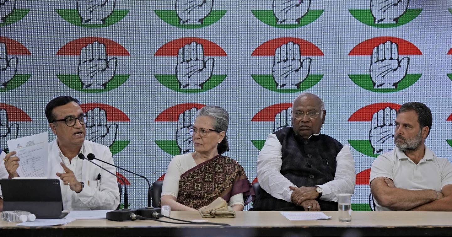Congress party treasurer Ajay Maken, left, speaks and displays the notice from Indian taxation authority as party president Mallikarjun Kharge, second right, and senior party leaders Sonia Gandhi, second left, and Rahul Gandhi listen during a press conference at their party headquarters in New Delhi, India, Thursday, March 21, 2024. (Credit: Manish Swarup/AP.)
