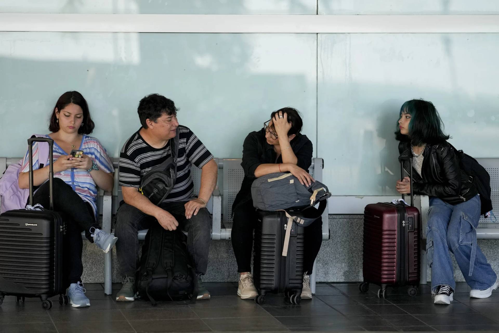 Tourists from Chile sit outside the Jorge Newbery airport after their flight was suspended in Buenos Aires, Argentina, Wednesday, Feb. 28, 2024. Airport and airline workers, as well as pilots, were staging a 24-hour strike for improved wages. (Credit: Natacha Pisarenko/AP.)