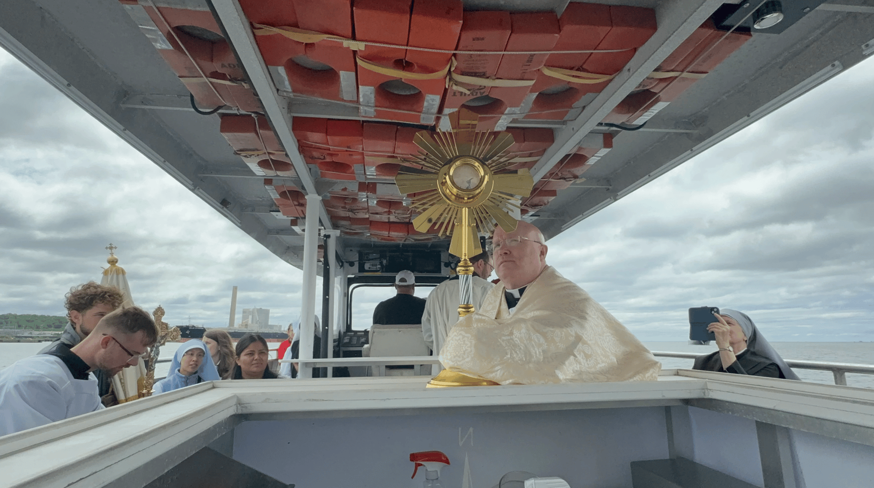 Father Roger Landry (center) pictured with the monstrance while taking a boat from New Haven to Bridgeport on day two of the National Eucharistic Pilgrimage. (Credit: Seton Pilgrimage Blog.)
