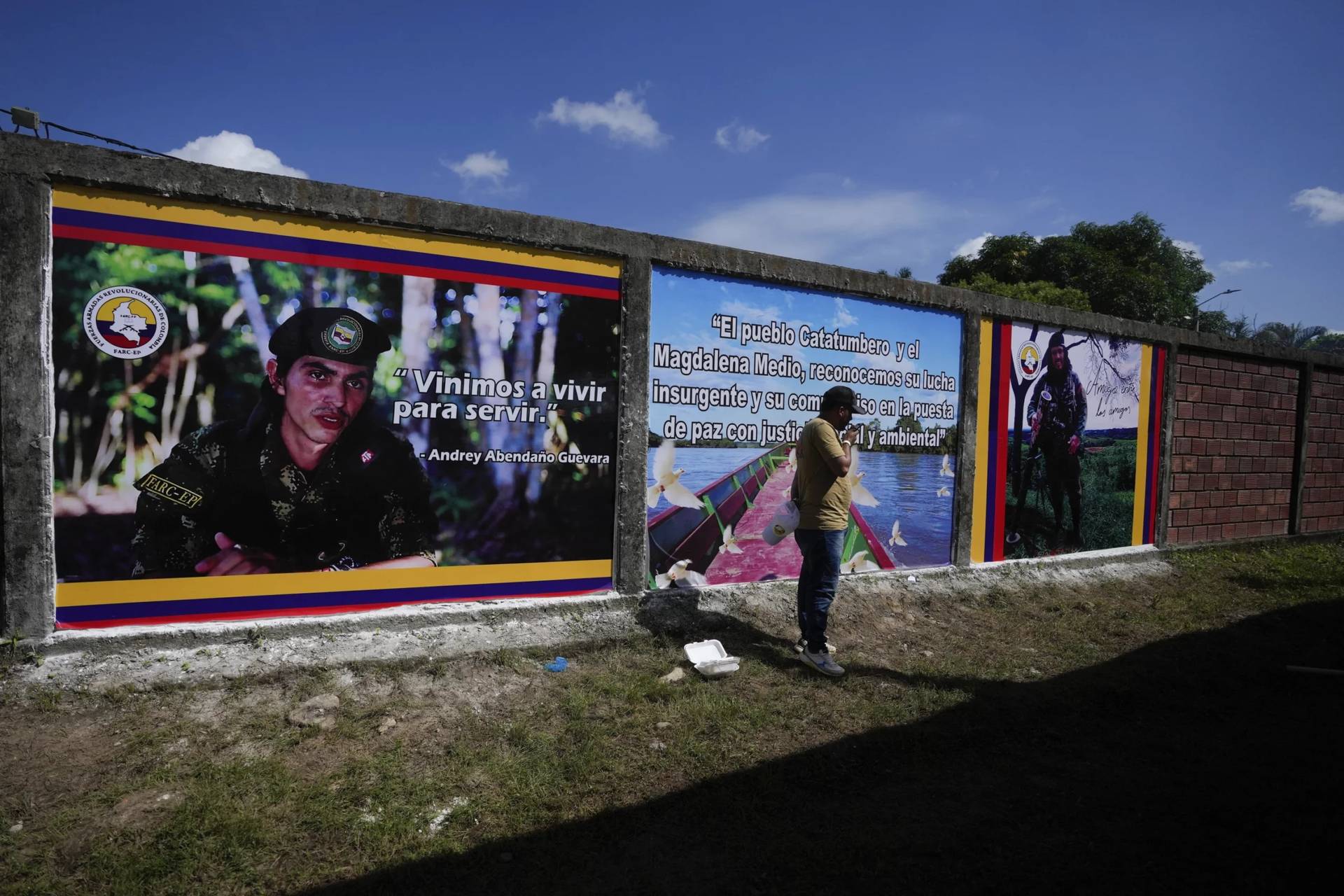 A man talks on his cellphone in front of a Revolutionary Armed Forces of Colombia, FARC, propaganda billboards of Andrey Avendano and other members of the Central General Staff of the FARC, before peace talks with the government of Colombia in Tibu, Colombia, Oct. 8, 2023. (Credit: Fernando Vergara/AP.)