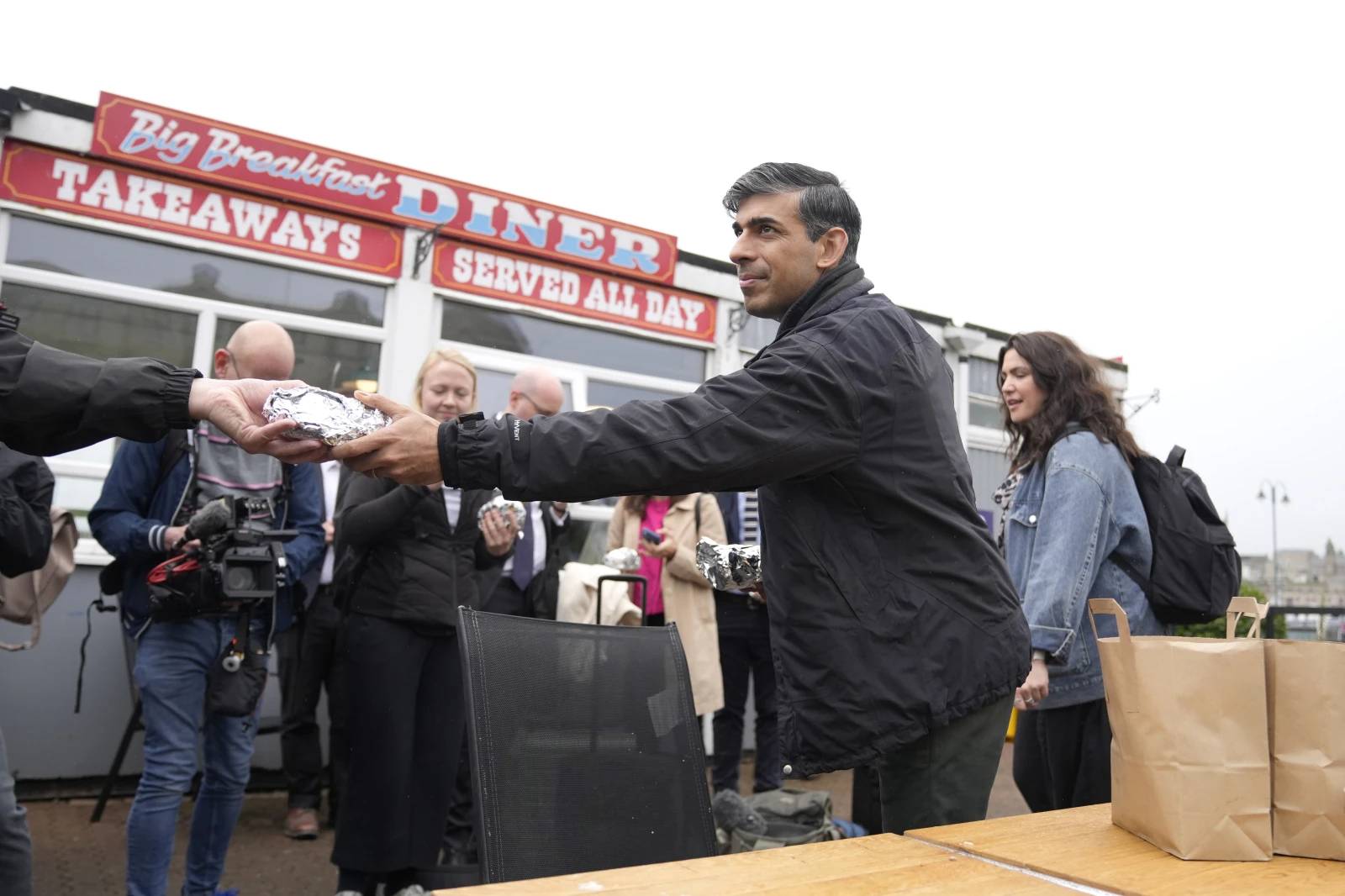 Britain’s Prime Minister Rishi Sunak buys breakfast for the travelling media as he arrives at a railway station for a Conservative general election campaign event in the South West of England, Wednesday, May 29, 2024. (Credit: Alastair Grant/AP Photo, Pool.)