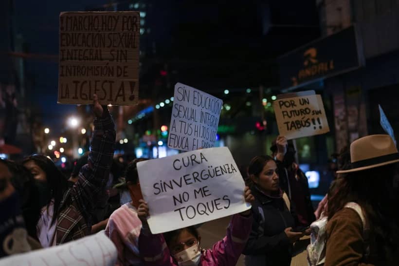 People protest with signs that read in Spanish “Shameless priest do not touch me” and “I march for sexual education without Church interference,” outside the offices of the Bolivian Episcopal Conference in La Paz, Bolivia, Monday, May 15, 2023. (Credit: Juan Karita/AP.)