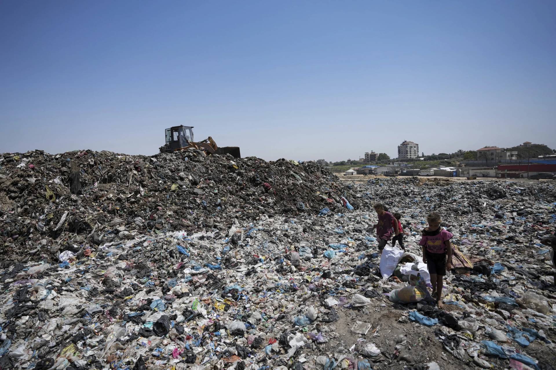 Palestinians sort through trash at a landfill in Nuseirat refugee camp in Gaza on June 20, 2024. (Credit: Kareem Hana/AP.)