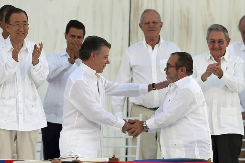 Colombia’s President Juan Manuel Santos, front left, and the top commander of the Revolutionary Armed Forces of Colombia, FARC, Rodrigo Londono, known by the alias Timochenko, shake hands after signing the peace agreement between the government and the FARC to end over 50 years of conflict, in Cartagena, Colombia, Sept. 26, 2016. (Credit: Fernando Vergara/AP.)