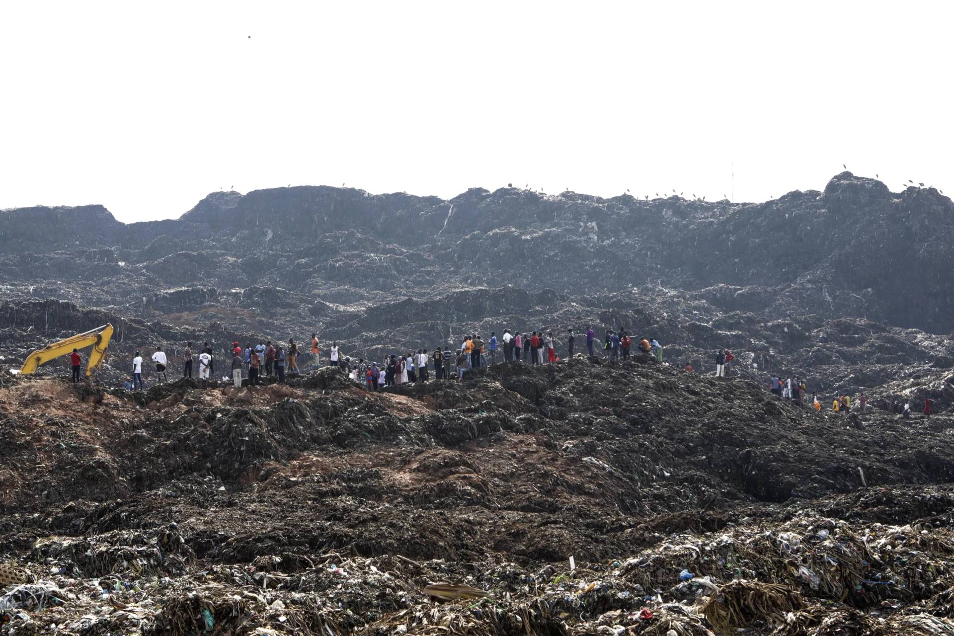 Onlookers watch as workers search for survivors at the site of a collapsed landfill in Kampala, Uganda, Sunday, Aug. 11, 2024. (Credit: Hajarah Nalwadda/AP.)