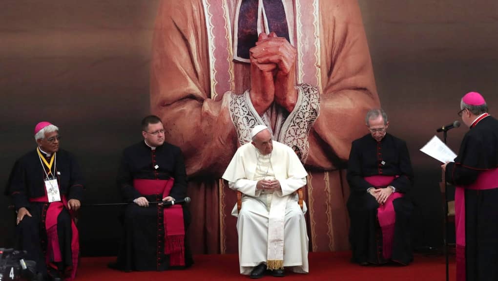 Sitting against a backdrop depicting St. John Vianney, patron saint of parish priests, Pope Francis listens to a welcome message by Bishop Jose Antonio Eguren, during a meeting with priests, religious men and women, and seminarians of the ecclesiastical provinces of Northern Peru in the St. Carlos and Marcelo College in Trujillo, Peru, Saturday, Jan. 20, 2018. (Credit: Alessandra Tarantino/AP.)