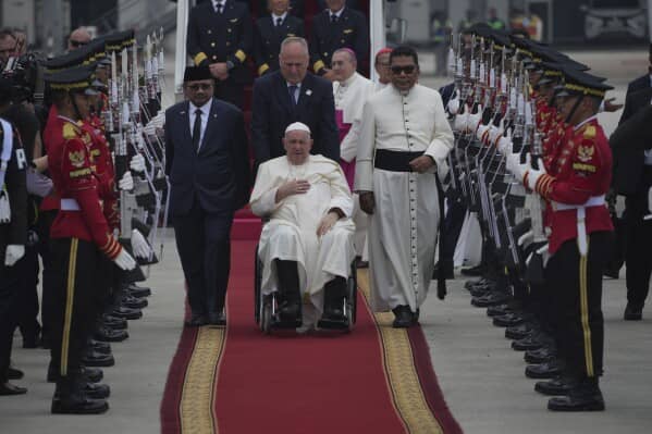 Pope Francis on his wheelchair, is welcomed as Indonesian Minister of Religious Affairs Yaqut Cholil Qoumas, center left, walks during an official welcoming ceremony at Soekarno-Hatta International Airport in Tangerang on the outskirts of Jakarta, Indonesia, Tuesday, Sept. 3, 2024. (Credit: Achmad Ibrahim/AP.)