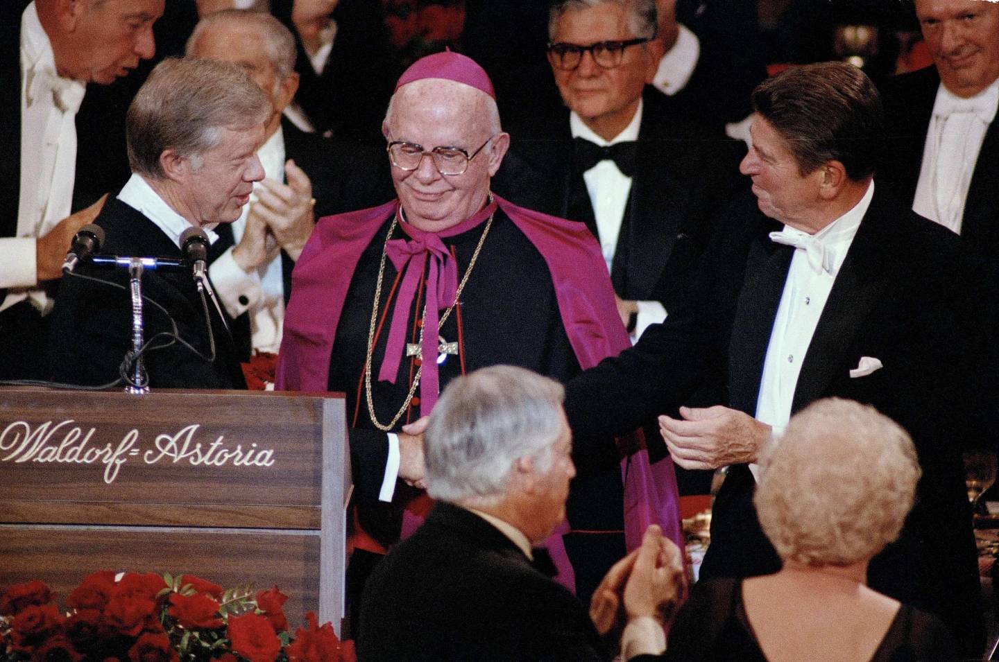 President Jimmy Carter shakes hands with his rival, Republican presidential nominee Ronald Reagan, at the Al Smith Astoria in New York, Oct. 16, 1980. Archbishop John J. Maguire, center, looks on. (Credit: Richard Drew/AP.)