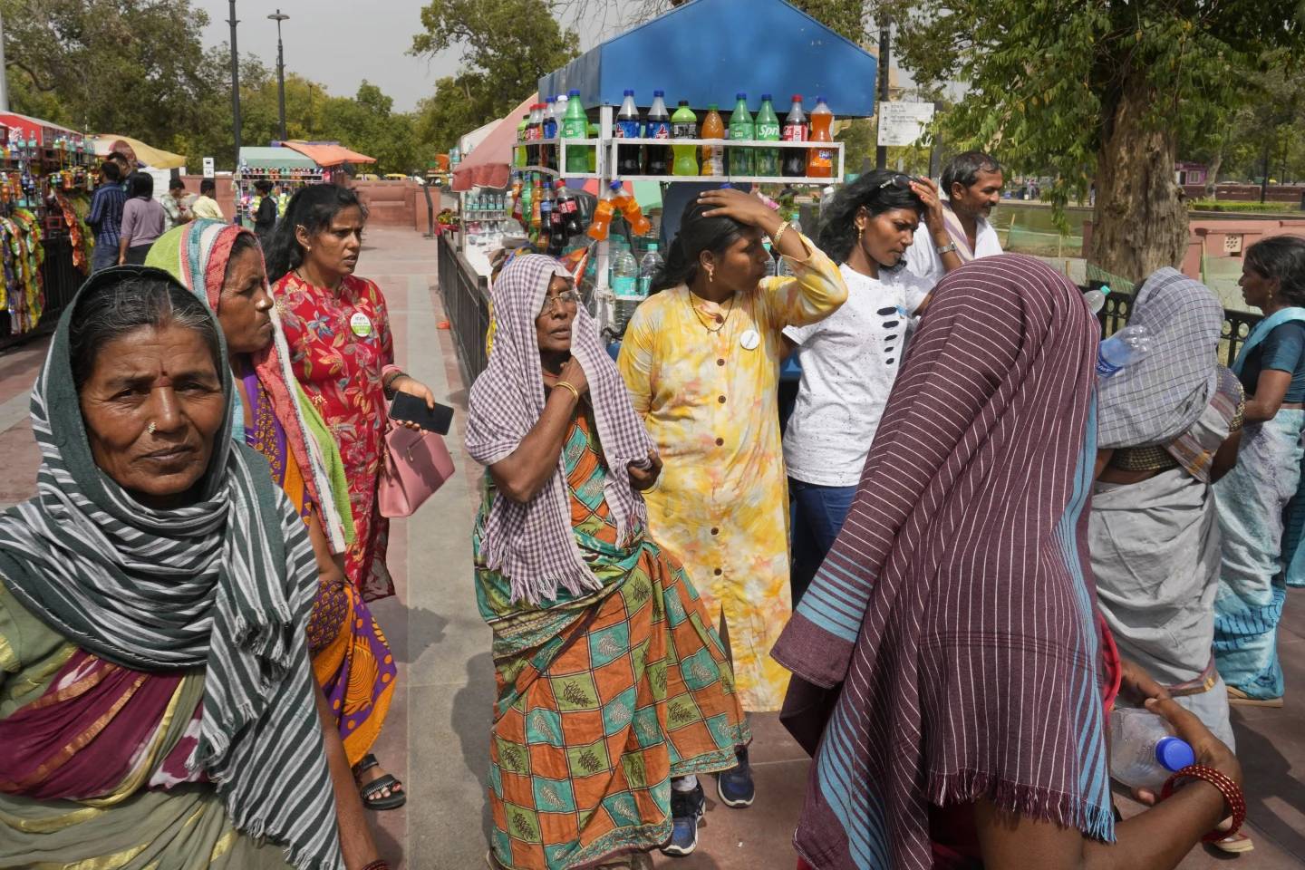 Local tourists cover their heads to shield from the heat as they buy drinking water bottles, in New Delhi, India, Tuesday, June 18, 2024. (Credit: Manish Swarup/AP.)