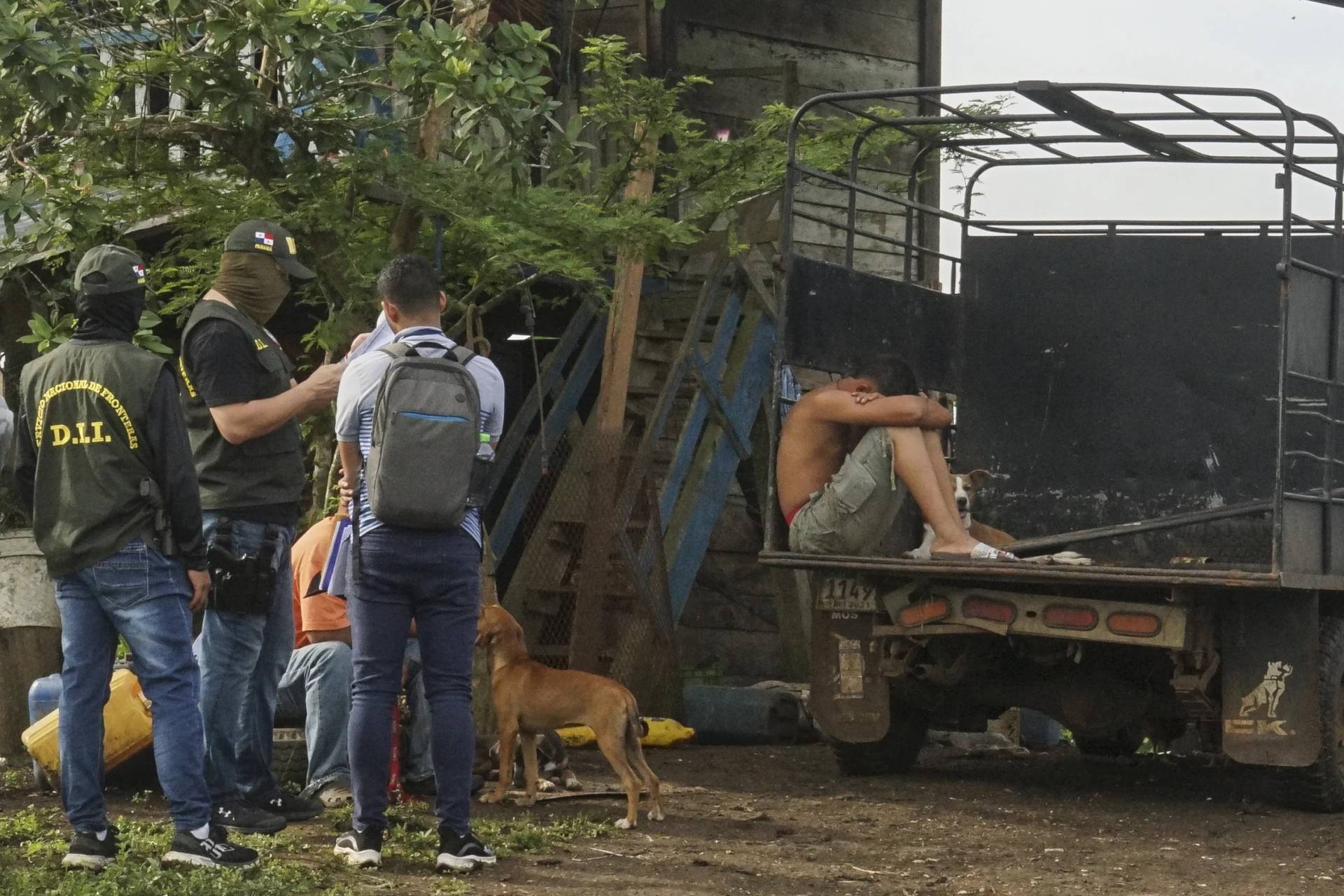 A detainee sits in a truck under watch by border police on the outskirts of Santa Fe in the Darien province of Panama, Wednesday, Aug. 7, 2024. Police arrested alleged human traffickers of migrants who enter through the Darien jungle on their way to the U.S. (Credit: Abraham Teran/AP.)