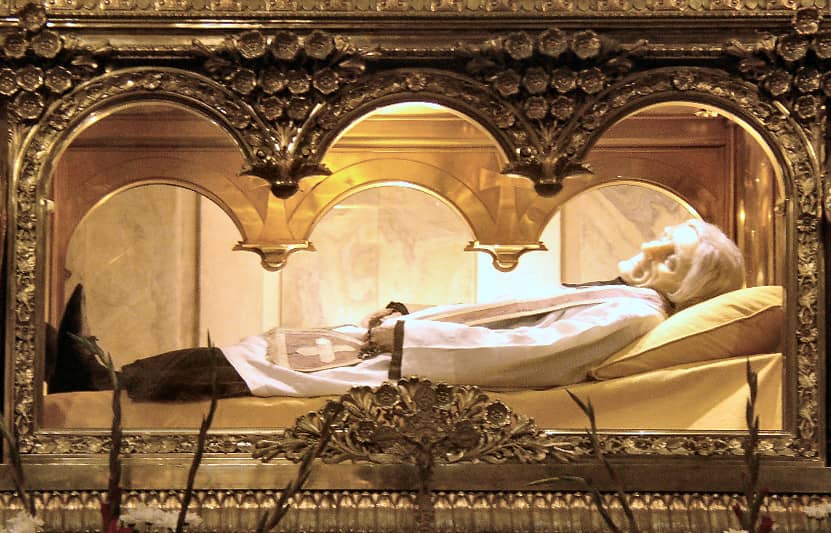 The body of Saint John Mary Vianney, entombed above the main altar in the Basilica at Ars, France. The face is covered with a wax mask. (Credit: Wikimedia.)