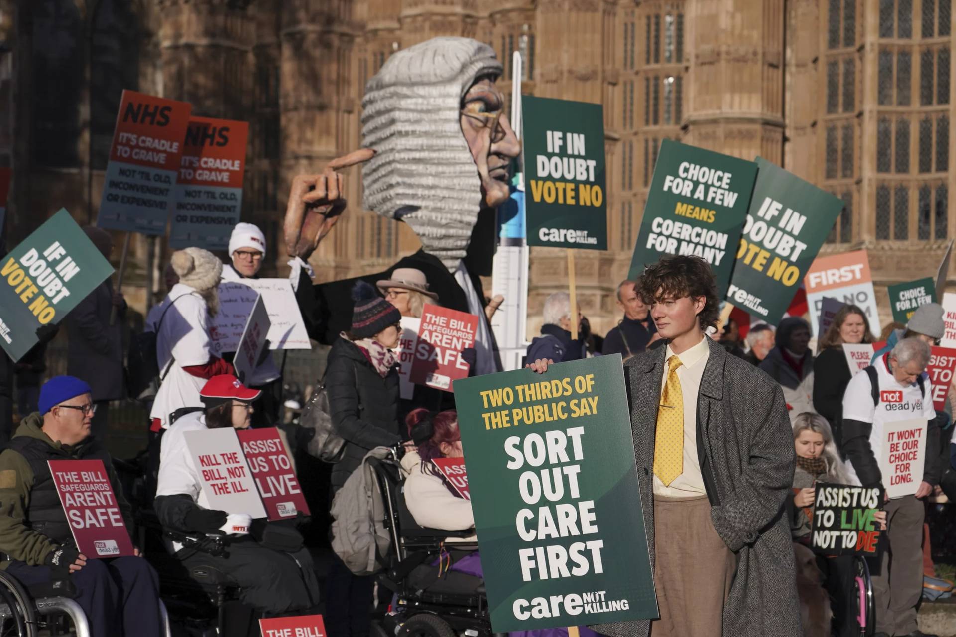 Protesters show posters and placards in front of Parliament in London, Friday, Nov. 29, 2024 as British lawmakers started a historic debate on a proposed to help terminally ill adults end their lives in England and Wales.(Credit: Alberto Pezzali/AP.)