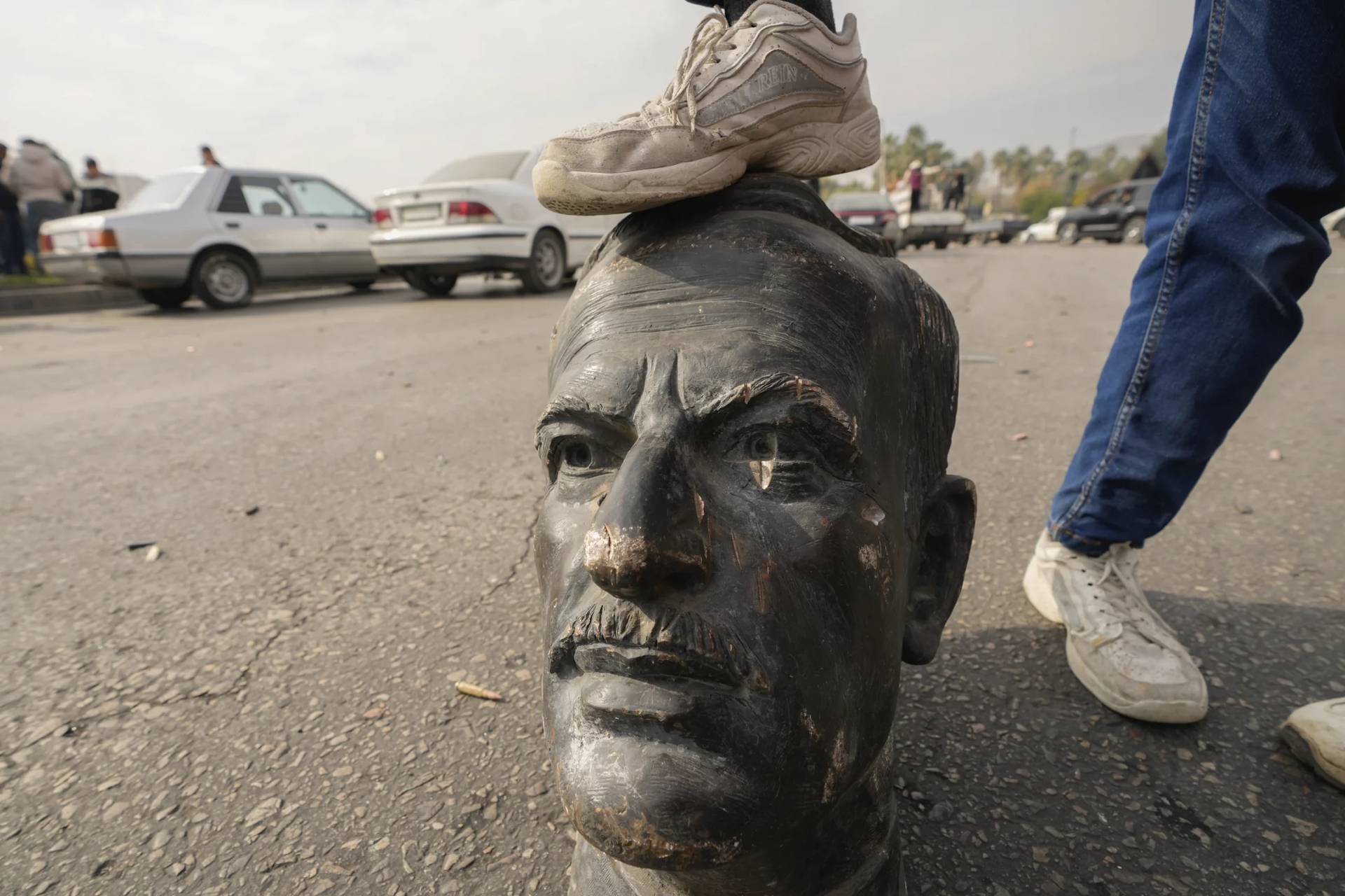 An opposition fighter steps on a broken bust of the late Syrian President Hafez Assad in Damascus, Syria, Sunday Dec. 8, 2024. (Credit: Hussein Malla/AP.)