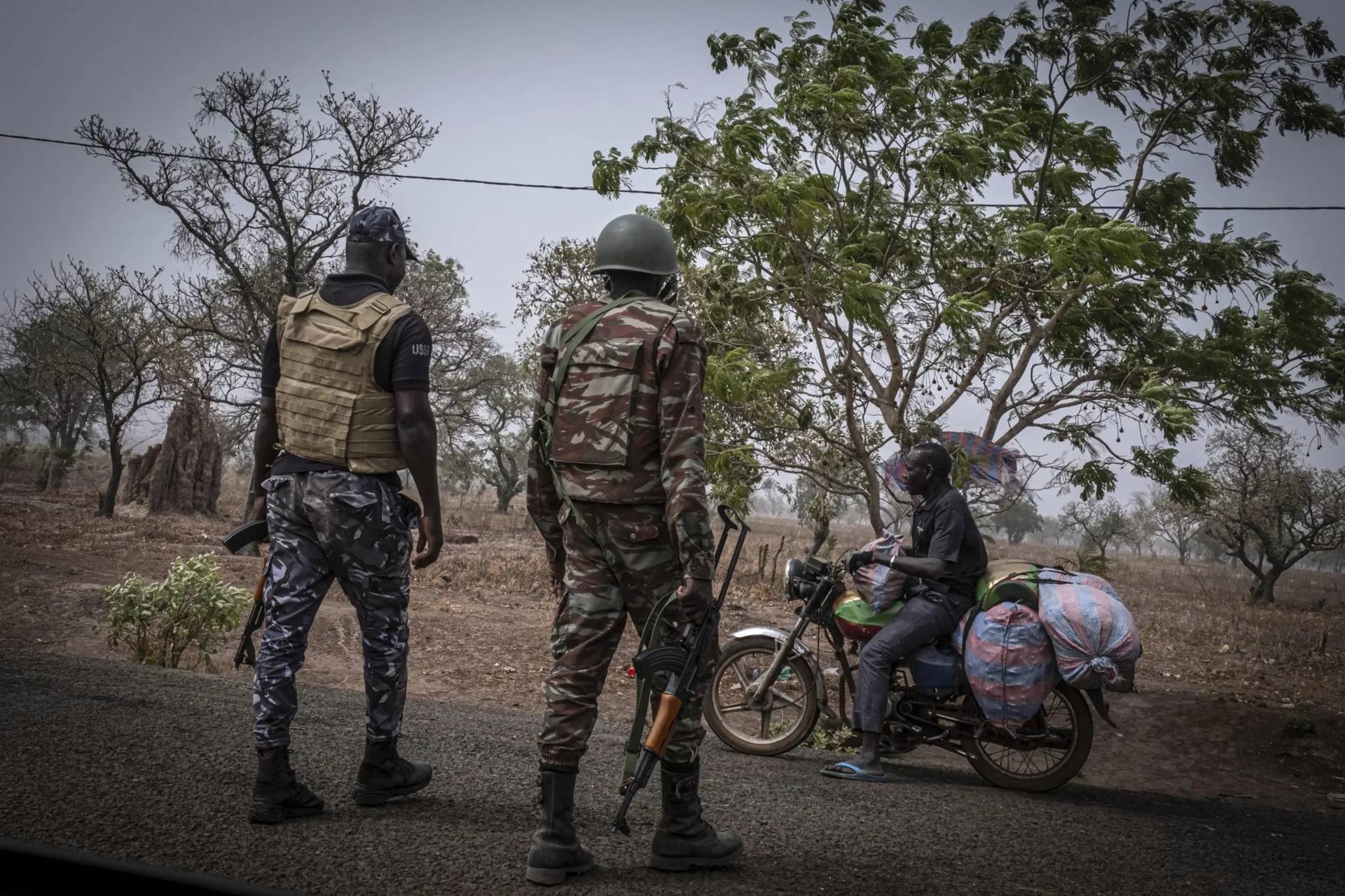 A police officer and a soldier stop a motorcycle at a checkpoint in Porga, Benin, on March 26, 2022. (Credit: Marco Simoncelli/AP.)