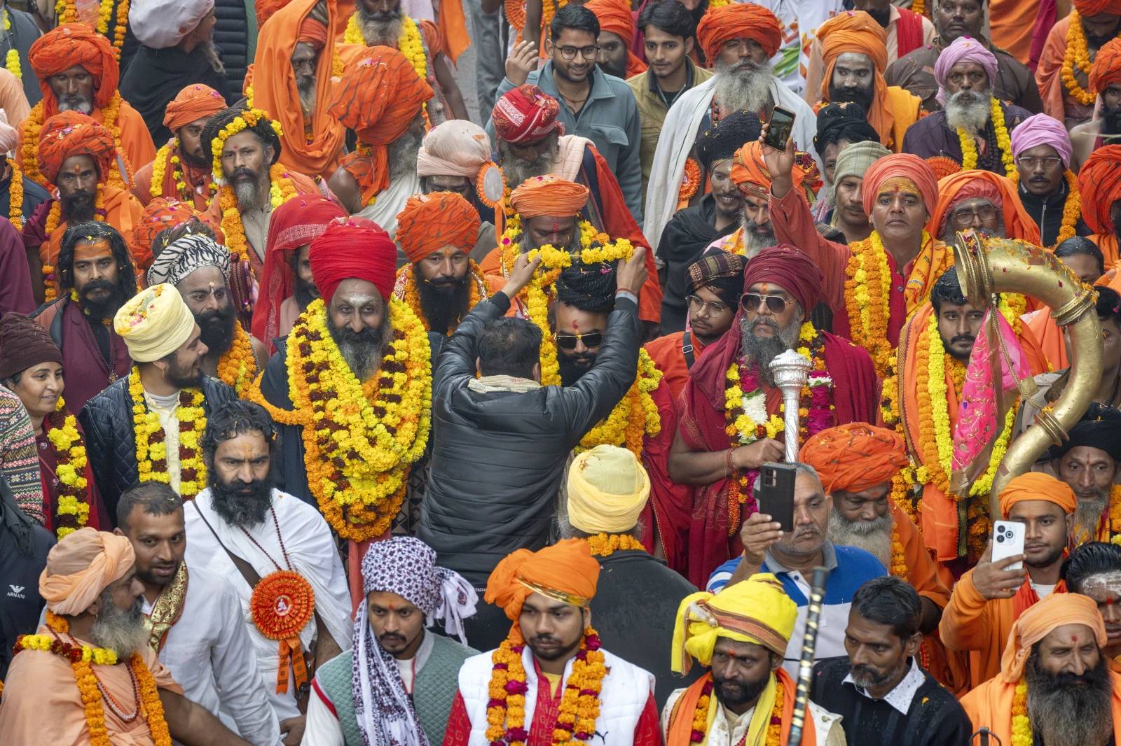 A devotee garlands a senior Hindu holy man walking in a procession, a day before the 45-day-long Maha Kumbh festival, in Prayagraj, India, Sunday, Jan. 12, 2025. (Credit: Ashwini Bhatia/AP.)