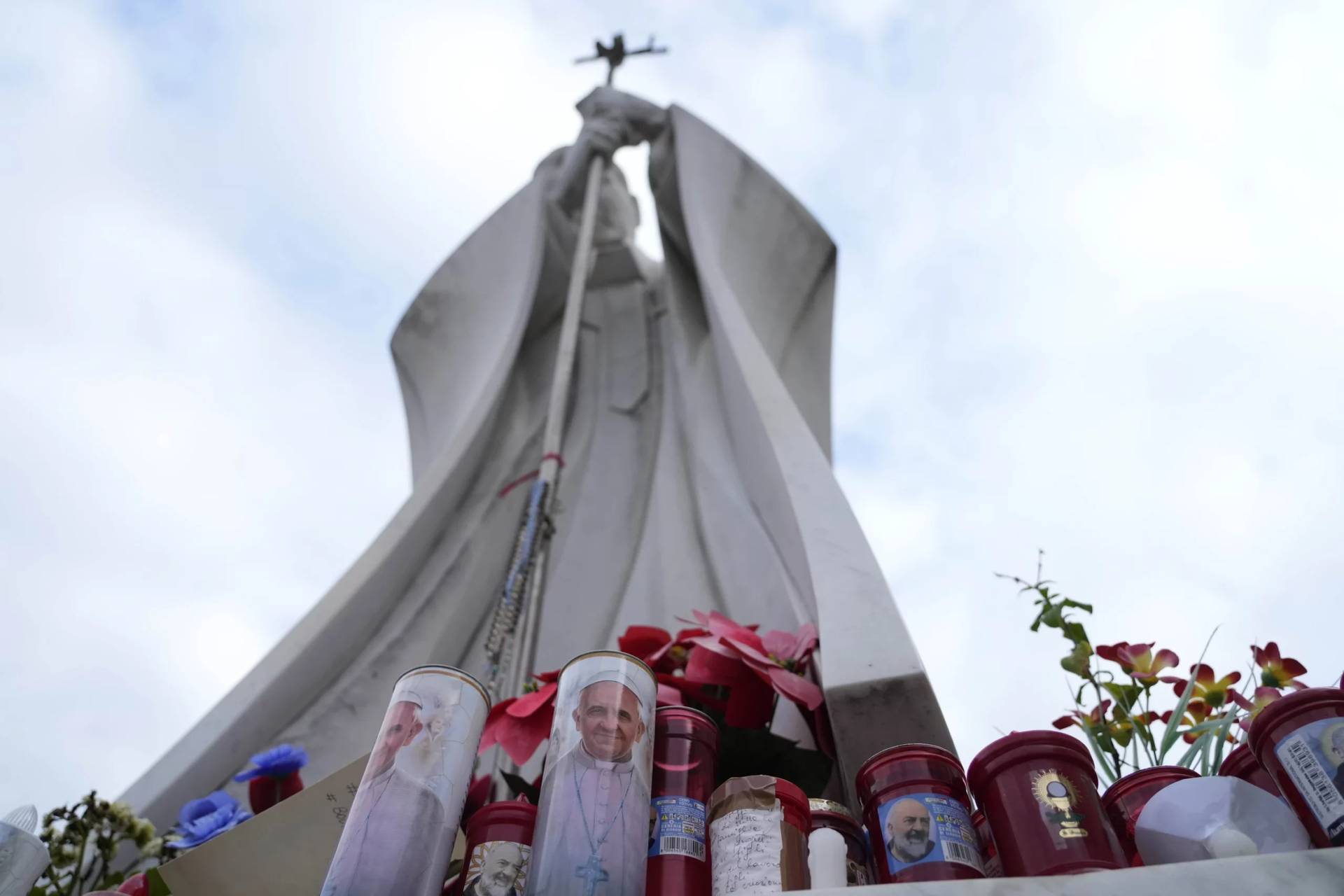 Candles with the pictures of Pope Francis are the laid under the statue of late Pope John Paul II outside Agostino Gemelli Polyclinic in Rome, Wednesday, Feb. 19, 2025, where the Pontiff is hospitalized since Friday, Feb. 14. (Credit: Gregorio Borgia/AP.)