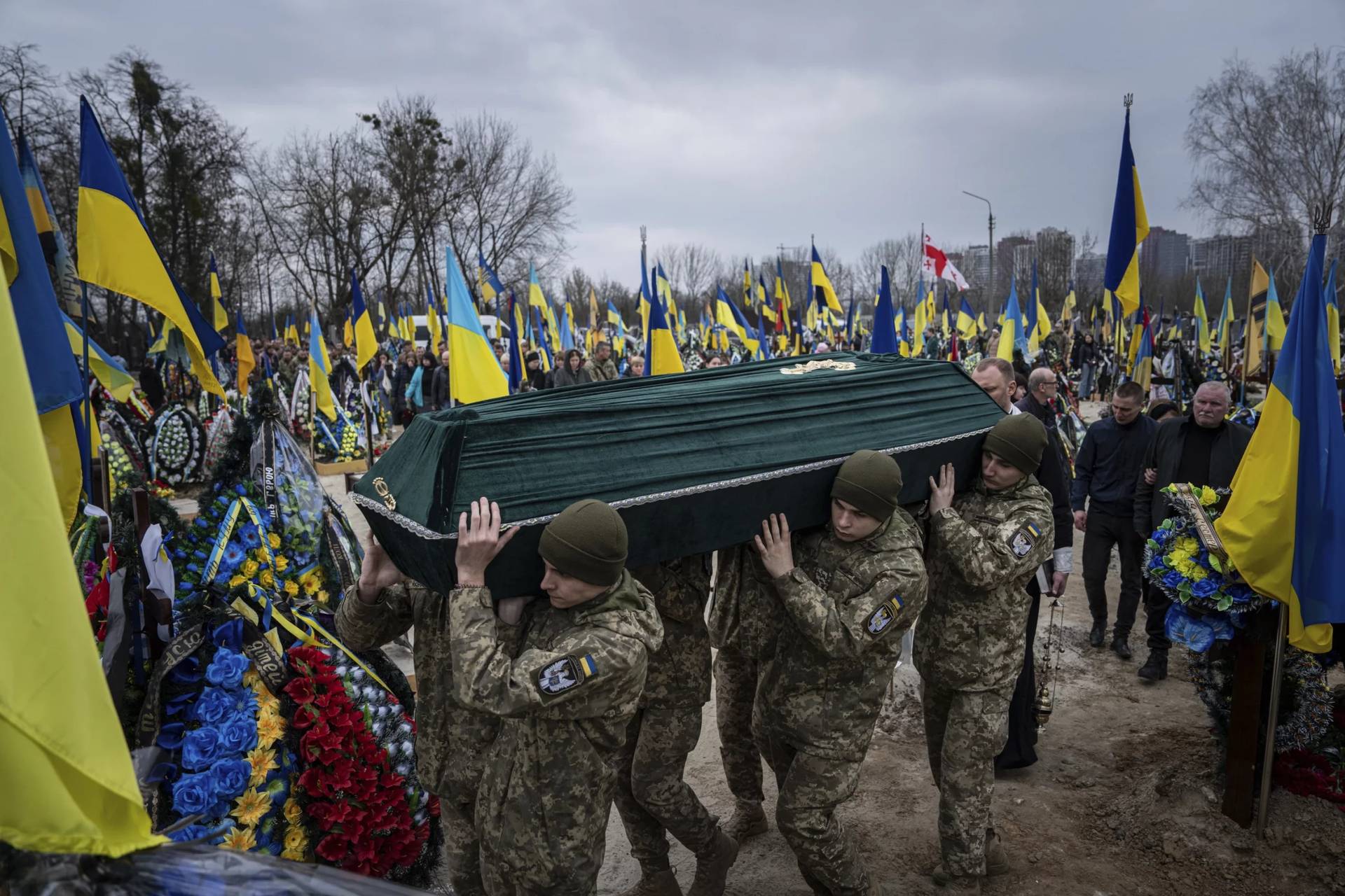 Ukrainian servicemen carry the coffin of their comrade Andrii Neshodovskiy during the funeral ceremony at the cemetery in Kyiv, Ukraine, Saturday, March 25, 2023. (Credit: Evgeniy Maloletka/AP.)