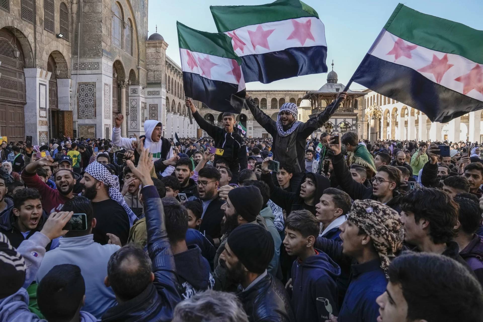 Demonstrators chant slogans and wave the new Syrian flag as they gather for Friday prayers at the Umayyad mosque in Damascus, Syria, on Friday, Dec. 13, 2024. (Credit: Leo Correa/AP.)