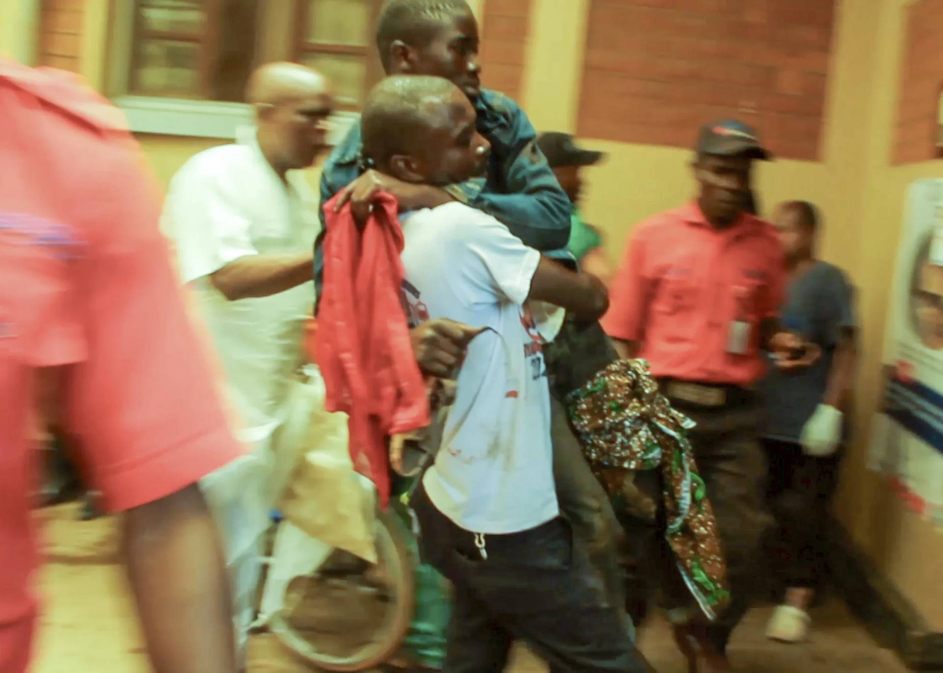 In this video frame grab, people assist victims after two explosions hit a meeting of M23 rebel group leaders and residents in Bukavu, eastern Congo, Thursday, Feb. 27, 2025. (Credit: Janvier Barhahiga/AP.)