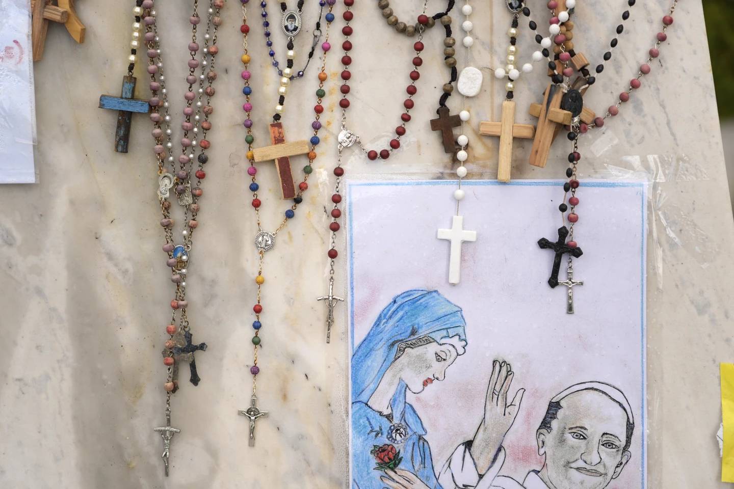 Rosaries are seen next to a drawing of Pope Francis outside of Rome’s Gemelli Hospital, March 16, 2025. (Credit: Gregorio Borgia/AP.)