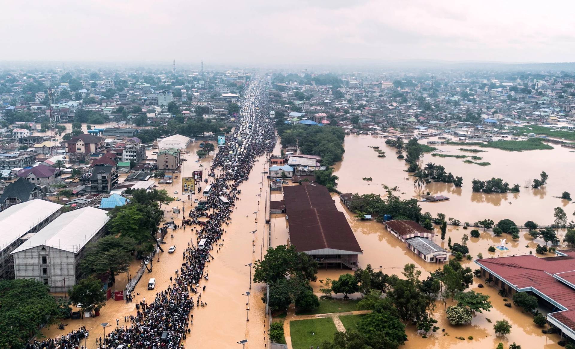 People walk through the flooded streets of Kinsasha, Democratic Republic of Congo, on April 6, 2025. (Credit: Samy Ntumba Shambuyi/AP.)