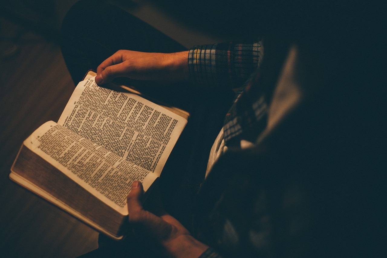 A man holds a Bible in prayer. (Credit: Pixabay.)