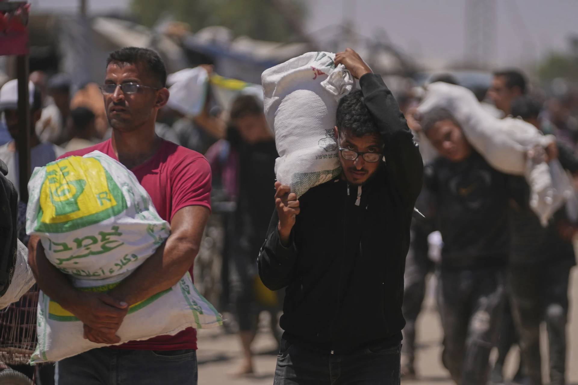 Palestinians carry bags containing food and humanitarian aid packages delivered by the Gaza Humanitarian Foundation, a U.S.-backed organization, in Rafah, southern Gaza Strip, Wednesday, June 25, 2025. (Credit: Abdel Kareem Hana/AP.)