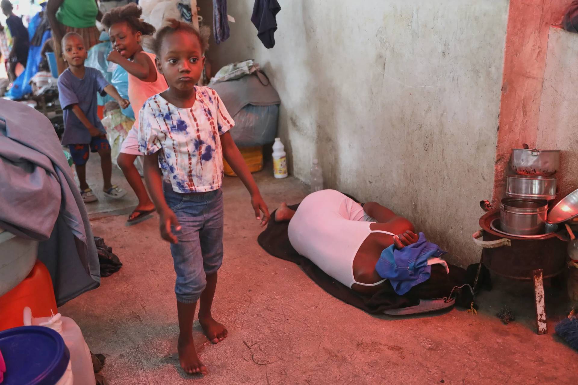 A woman sleeps on a blanket next to children playing in a shelter for families displaced by gang violence in Port-au-Prince, Haiti, on May 12, 2025. (Credit: Odelyn Joseph/AP.)