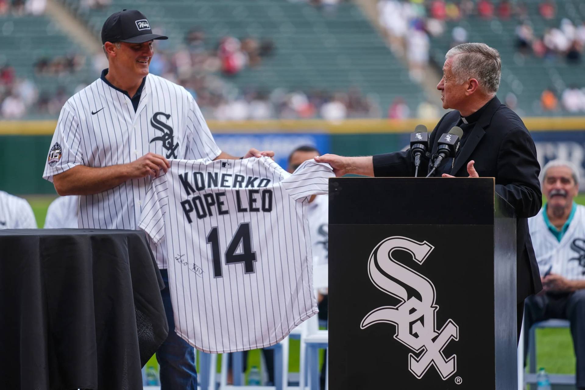 Cardinal Blase Cupich presents former Chicago White Sox player Paul Konerko with a jersey signed by Pope Leo XIV during a ceremony honoring the 2005 World Series Champions before a baseball game between the Cleveland Guardians and Chicago White Sox on July 12, 2025. (Credit: Erin Hooley/AP.)