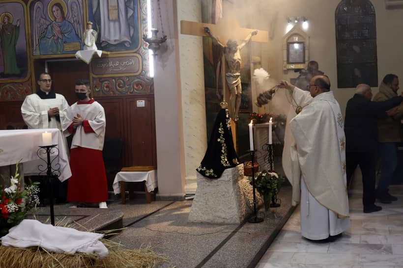 Father Gabriel Romanelli, Latin parish priest of Gaza Strip, left, prays during the midnight Christmas Eve mass at Deir Al Latin Holy Family Catholic Church in Gaza City, Dec. 24, 2021. (Credit: Adel Hana/AP.)