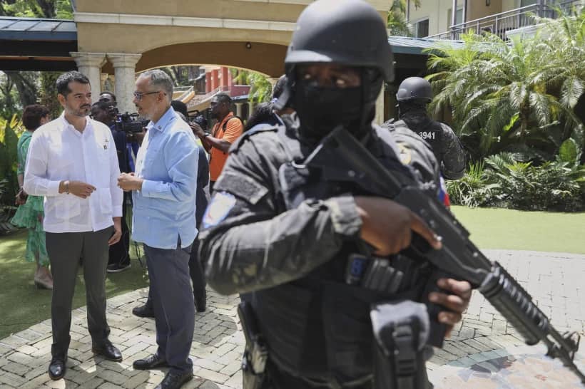 Security guards stand watch as Haiti’s Prime Minister Alix Didier Fils-Aime, center, talks with the Mexico’s Charge d’Affaires Jesus Cisneros after attending an event marking one year since the start of the Multinational Security Support Mission in Port-au-Prince, Haiti, Thursday, June 26, 2025. (Credit: Odelyn Joseph/AP.)