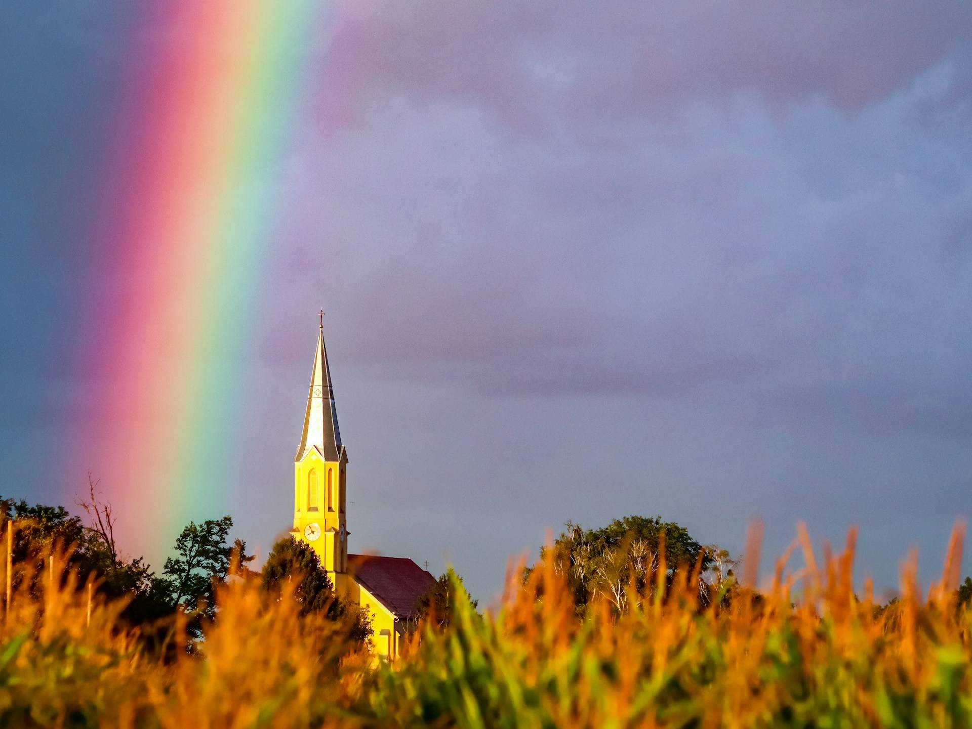 A rainbow by a church. (Credit: Nikola Tomašić/Unsplash.)