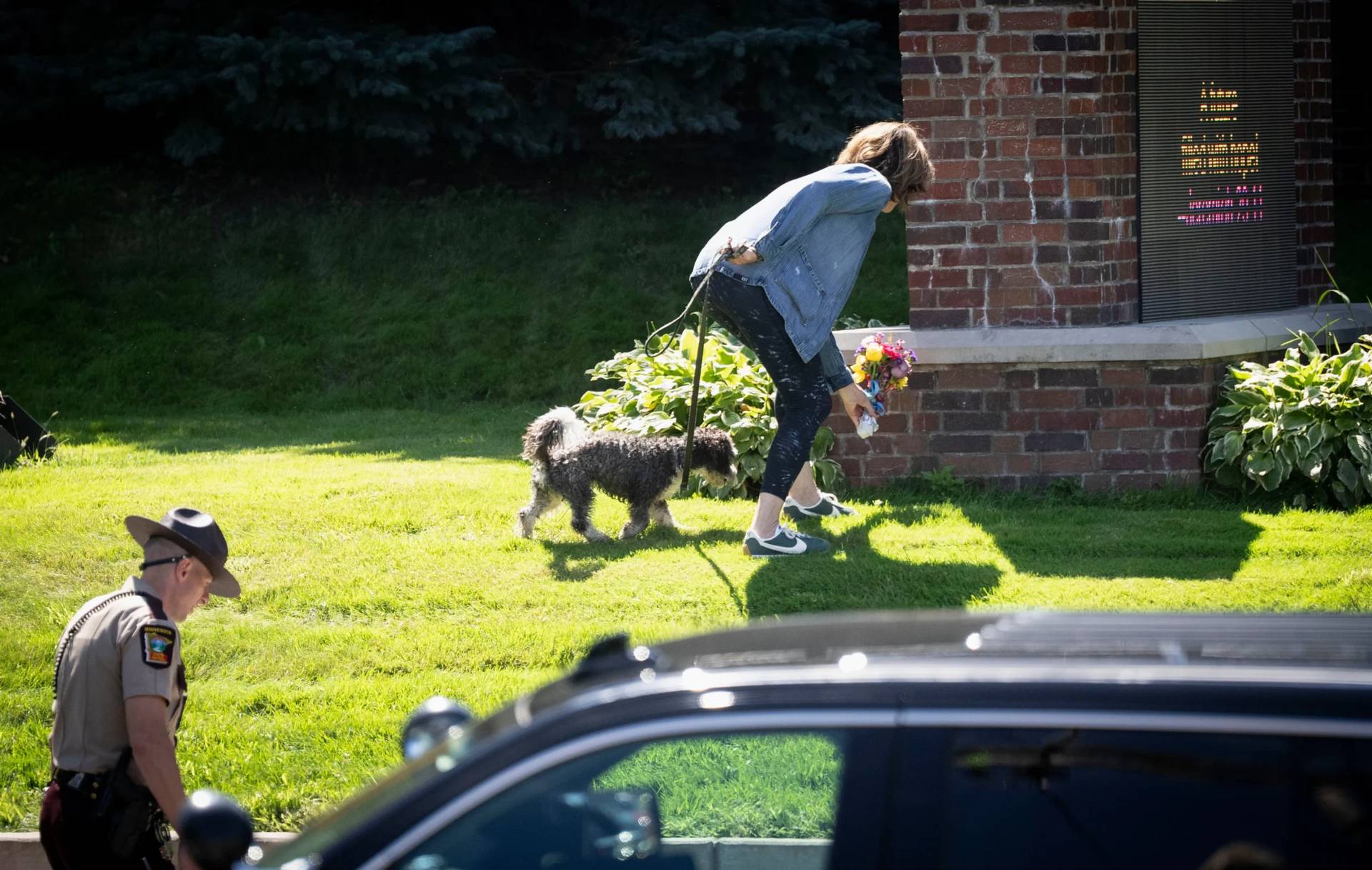 A woman is allowed to drop off flowers at the Annunciation Catholic School sign near the scene of the shooting at the school in Minneapolis on Aug. 27, 2025. (Credit: Renee Jones Schneider/Star Tribune via AP.)