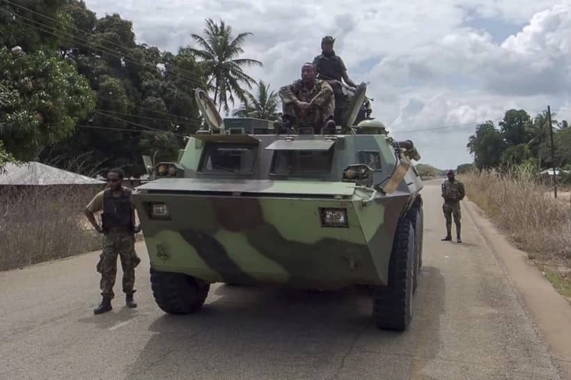 In this image made from video, Mozambican soldiers ride on an armored vehicle in a convoy driving to Mocimboa da Praia, Cabo Delgado province, Mozambique, Aug. 9, 2021. (Credit: Marc Hoogsteyns/AP.)
