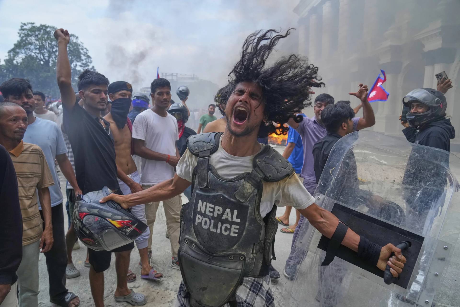 A protester wearing flak jacket and carrying a shield snatched from a policeman shouts slogans at the Singha Durbar, the seat of Nepal’s government’s various ministries and offices during a protest against social media ban and corruption in Kathmandu, Nepal, Tuesday, Sept. 9, 2025. (Credit: Niranjan Shrestha/AP.)