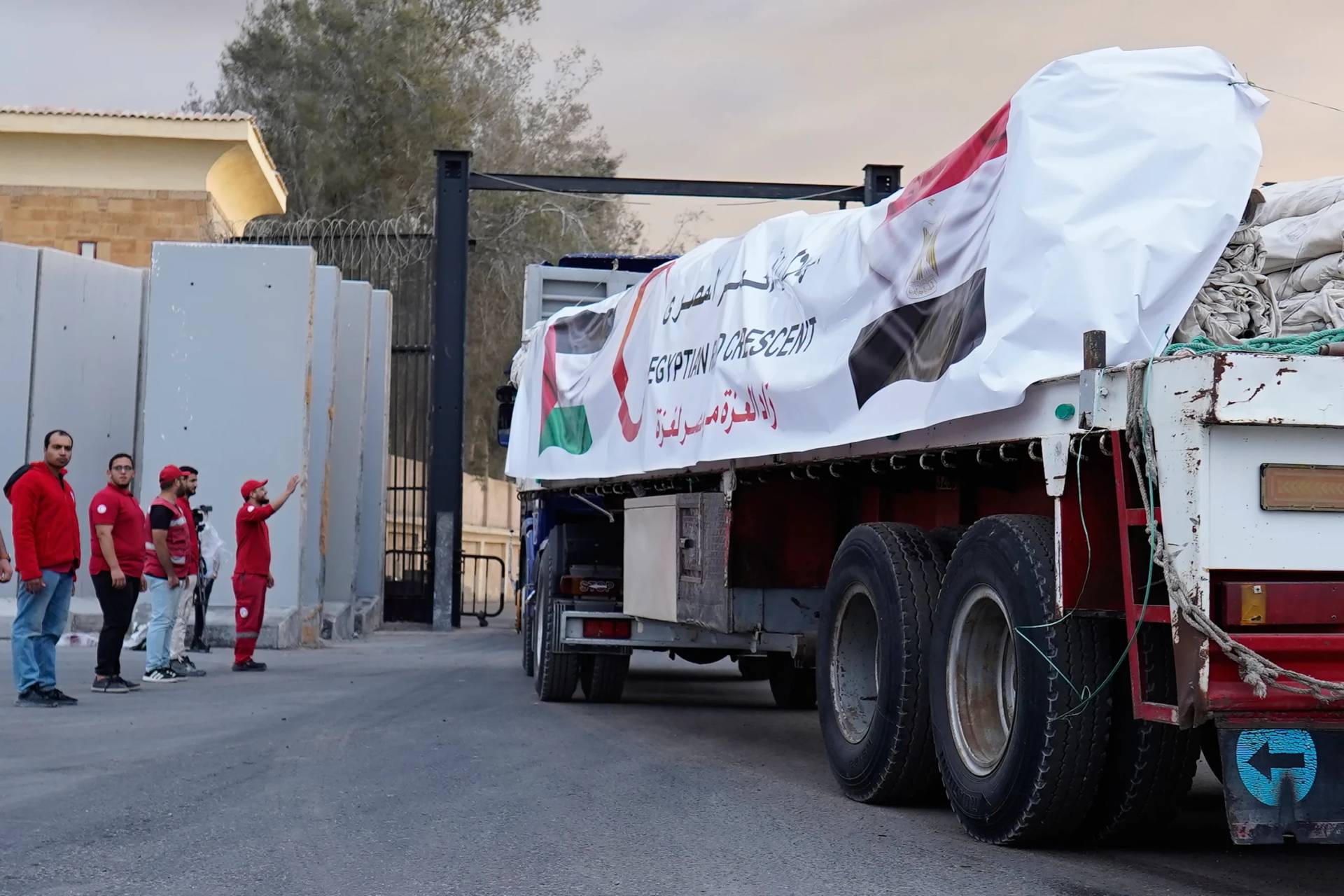 Egyptian Red Crecent members monitor trucks carrying humanitarian aids as they enter the Rafah crossing between Egypt and the Gaza Strip, following an agreement between Israel and Hamas on a ceasefire, Sunday, Oct. 12, 2025. (Credit: Mohamed Arafat/AP.)