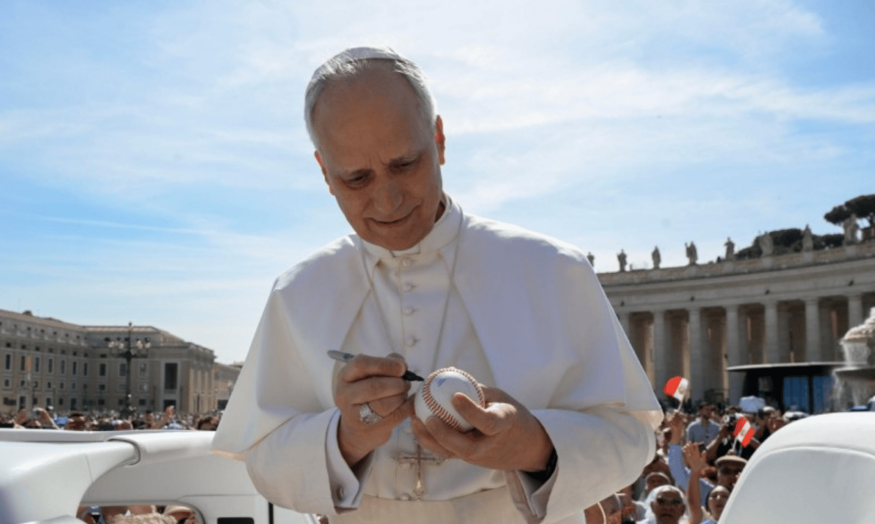 Pope Leo XIV signs a baseball in St. Peter's Square at the Vatican. (Credit: Vatican Media.)