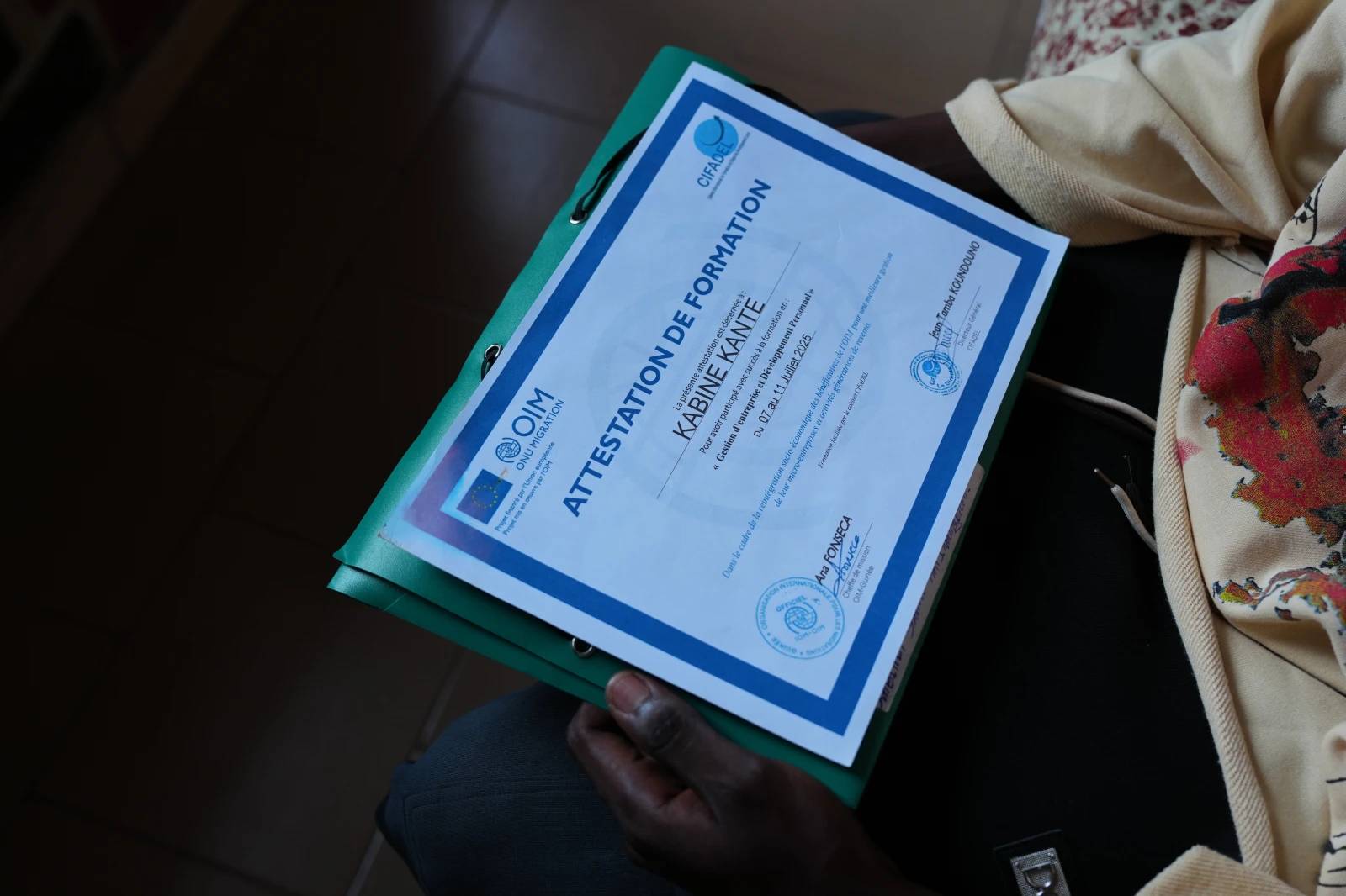 A returnee holds a training certificate issued by the International Organization for Migration (IOM) in Conakry, Guinea, Sept. 18, 2025. (Credit: Misper Apawu/AP.)
