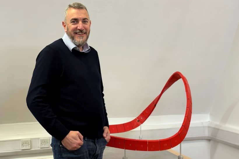 Richard Gamble, who said God spoke to him and gave him a vision for Eternal Wall of Answered Prayer in 2004, stands beside a model of the monument, Wednesday, Nov. 12, 2025, at his office in Coleshill, England. (Credit: Yonat Shimron/Religion News Service via AP.)