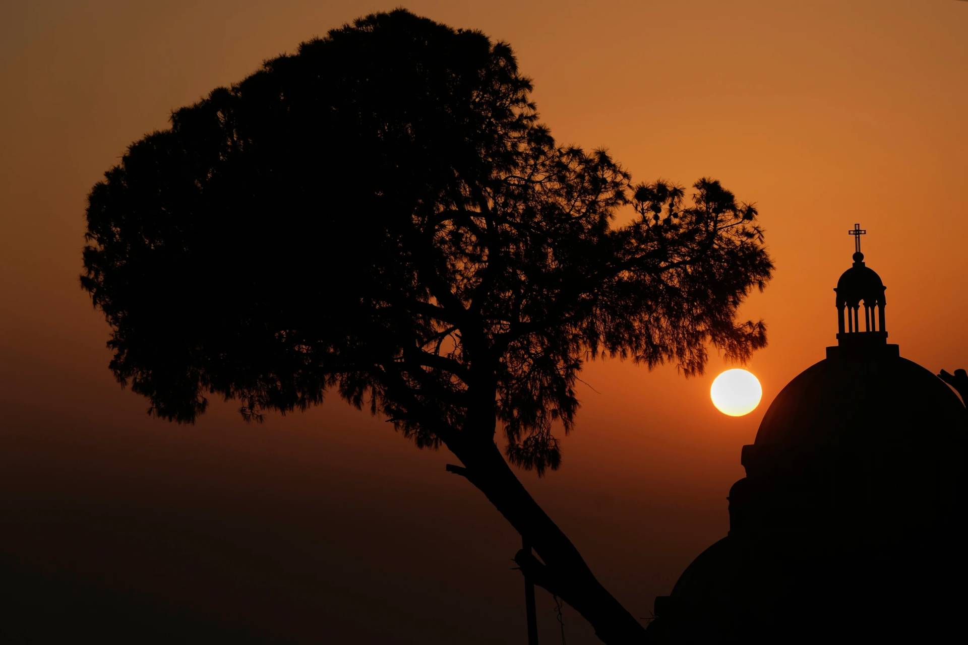The sun sets behind the dome of the Melkite Greek Catholic Basilica of Saint Paul in Harissa, east of Beirut, Lebanon, Sunday, Nov. 9, 2025. (Credit: Hassan Ammar/AP.)
