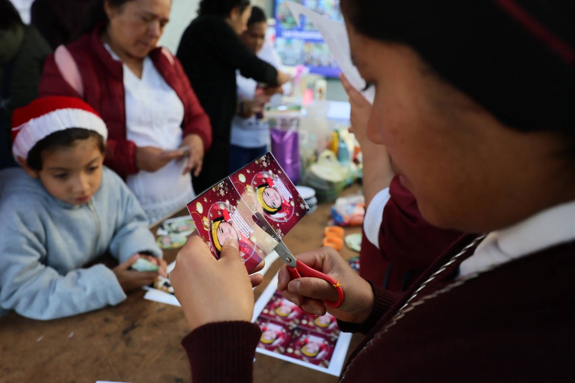 Sister Maria Elena cuts a photograph of a missing girl to paste on a Christmas ornament on the Tree of Hope in the Cathedral in Ecatepec, Mexico, on Nov. 17, 2025. (Credit: Ginnette Riquelme/AP.)