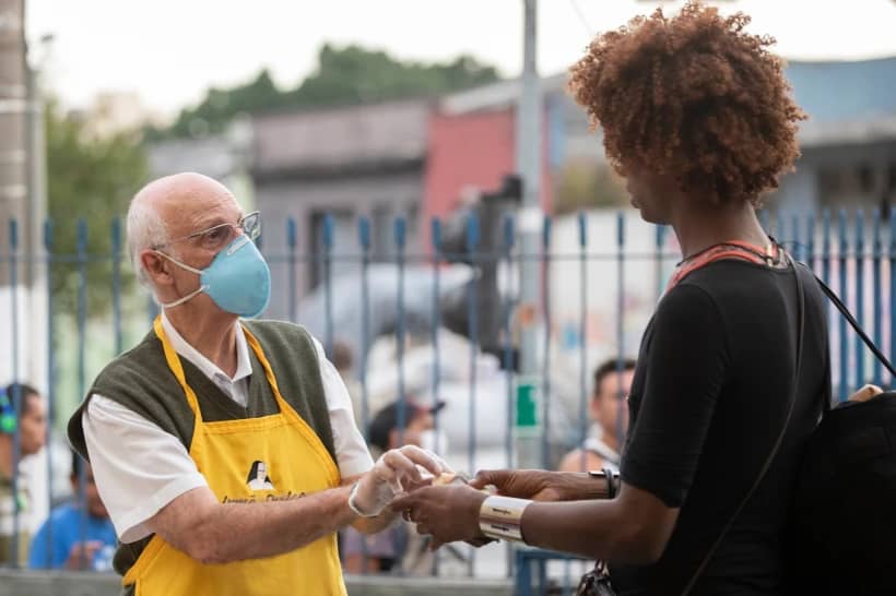Father Julio Lancellotti hands food to a homeless person in Sao Paulo, Brazil, April 3, 2020. (Credit: Andre Penner/AP.)