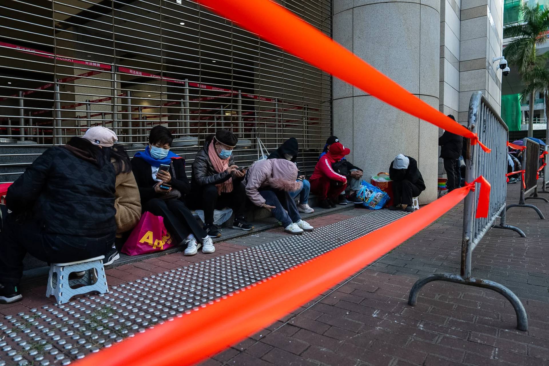 People wait to enter the West Kowloon Magistrates’ Courts ahead of the verdict for Hong Kong activist publisher Jimmy Lai’s national security trial, in Hong Kong, Monday, Dec. 15, 2025. (Credit: Chan Long Hei/AP.)