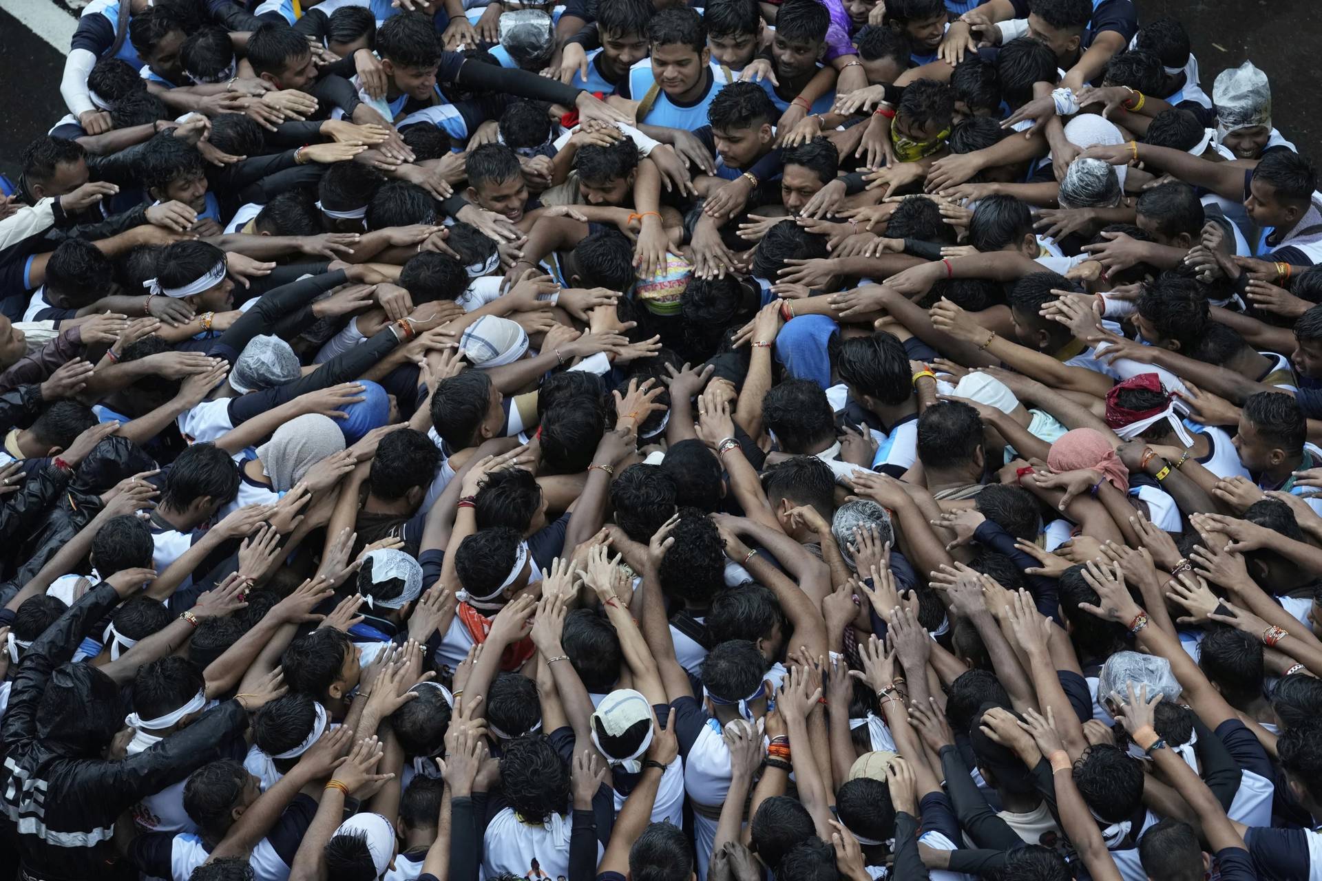 Devotees try to form a human pyramid to break a clay pot containing curd hanging above during the celebrations to mark the Hindu festival of Janmashtami in Mumbai, India, Saturday, Aug. 16, 2025. (Credit: Rajanish Kakade/AP.)