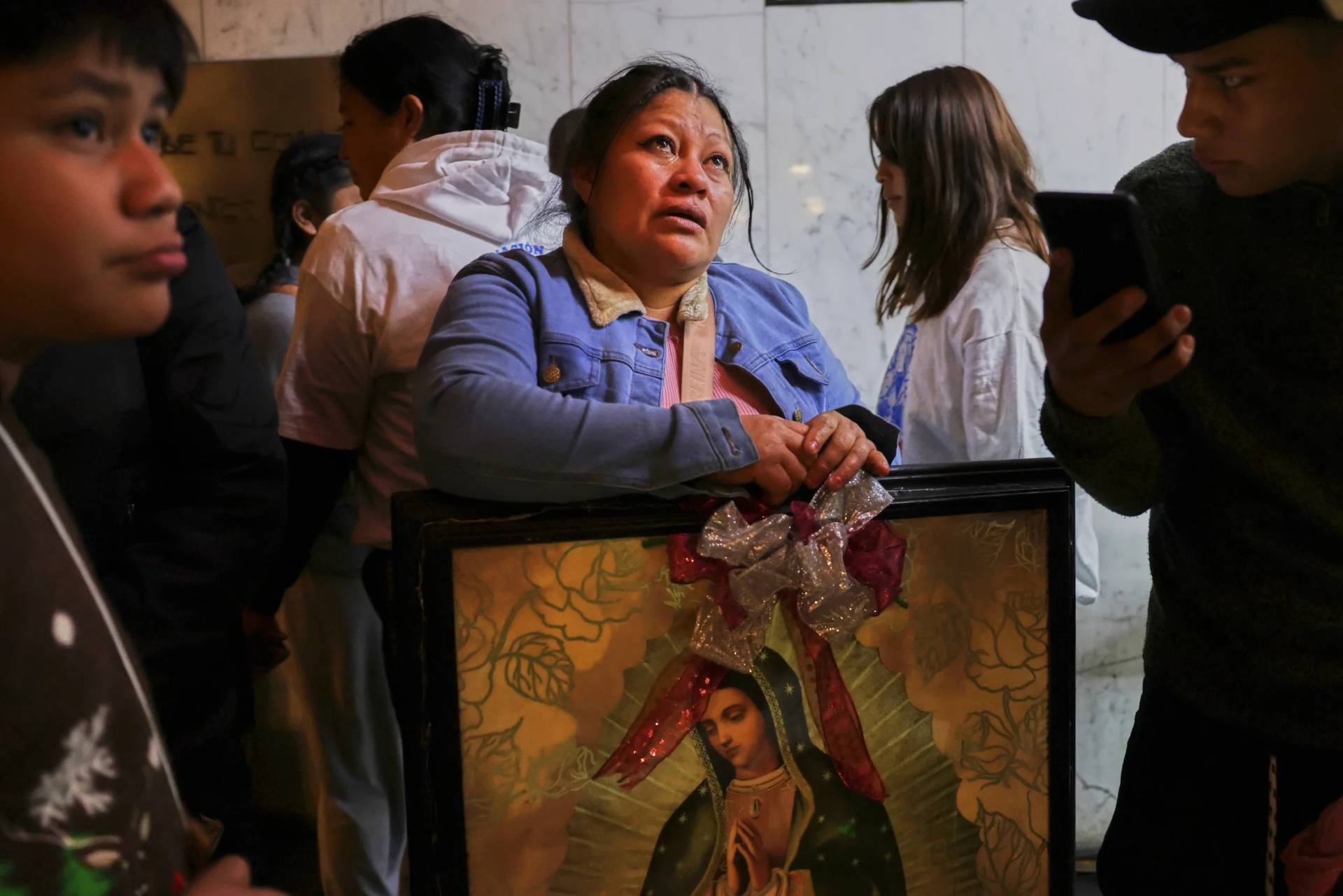 A woman cries as she looks up at the Virgin of Guadalupe image handing on the wall at the Basilica of Our Lady of Guadalupe in Mexico City, on her feast day, Friday, Dec. 12, 2025. (Credit: Claudia Rosel/AP.)