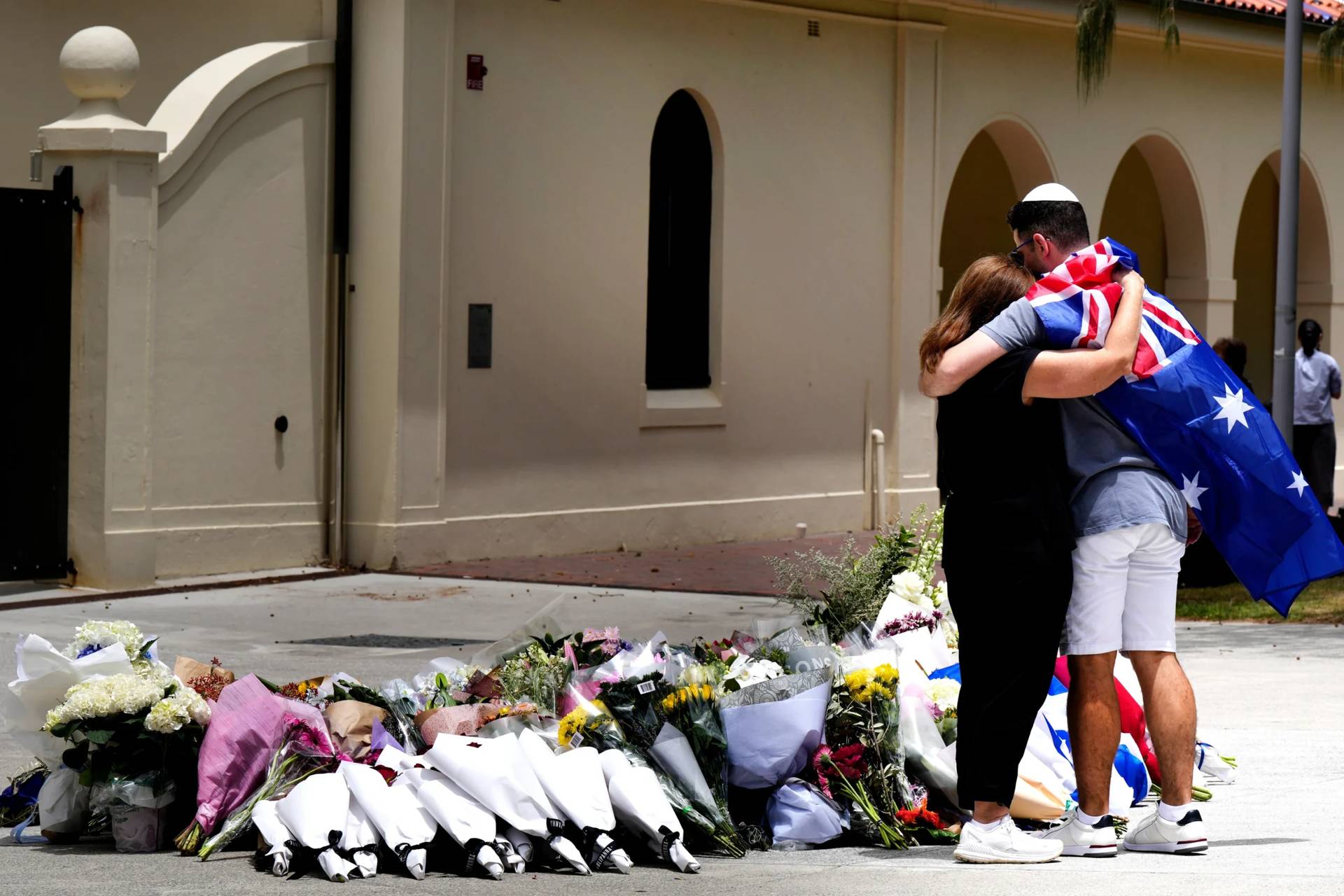 A couple lay flowers at a tribute to shooting victims outside the Bondi Pavilion at Sydney’s Bondi Beach, Monday, Dec. 15, 2025, a day after a shooting. (Credit: Mark Baker/AP.)