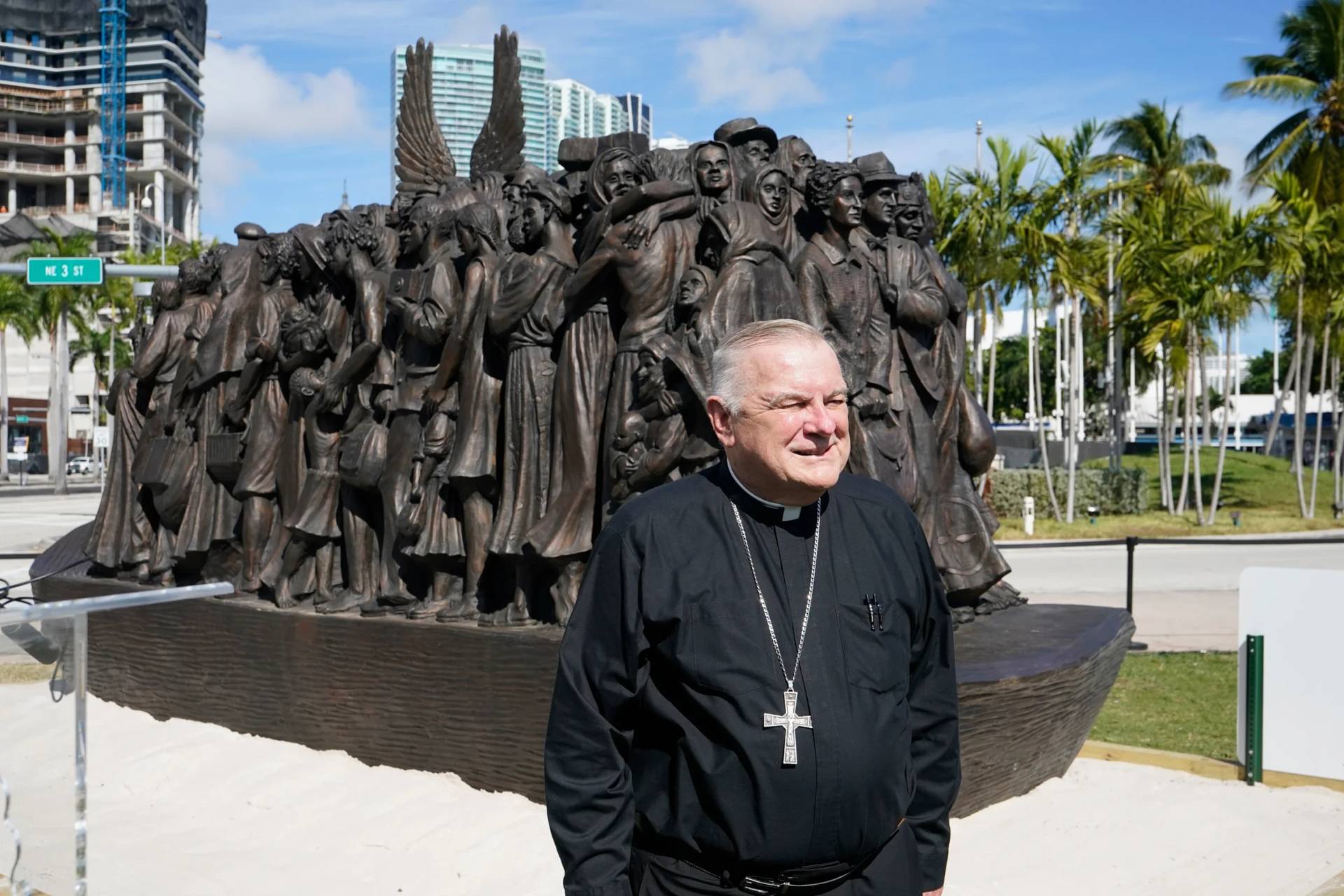 Archbishop of Miami Thomas Wenski poses in front of a traveling bronze sculpture titled "Angels Unawares," before blessing it, Feb. 10, 2021, in downtown Miami. (Credit: Wilfredo Lee/AP.)