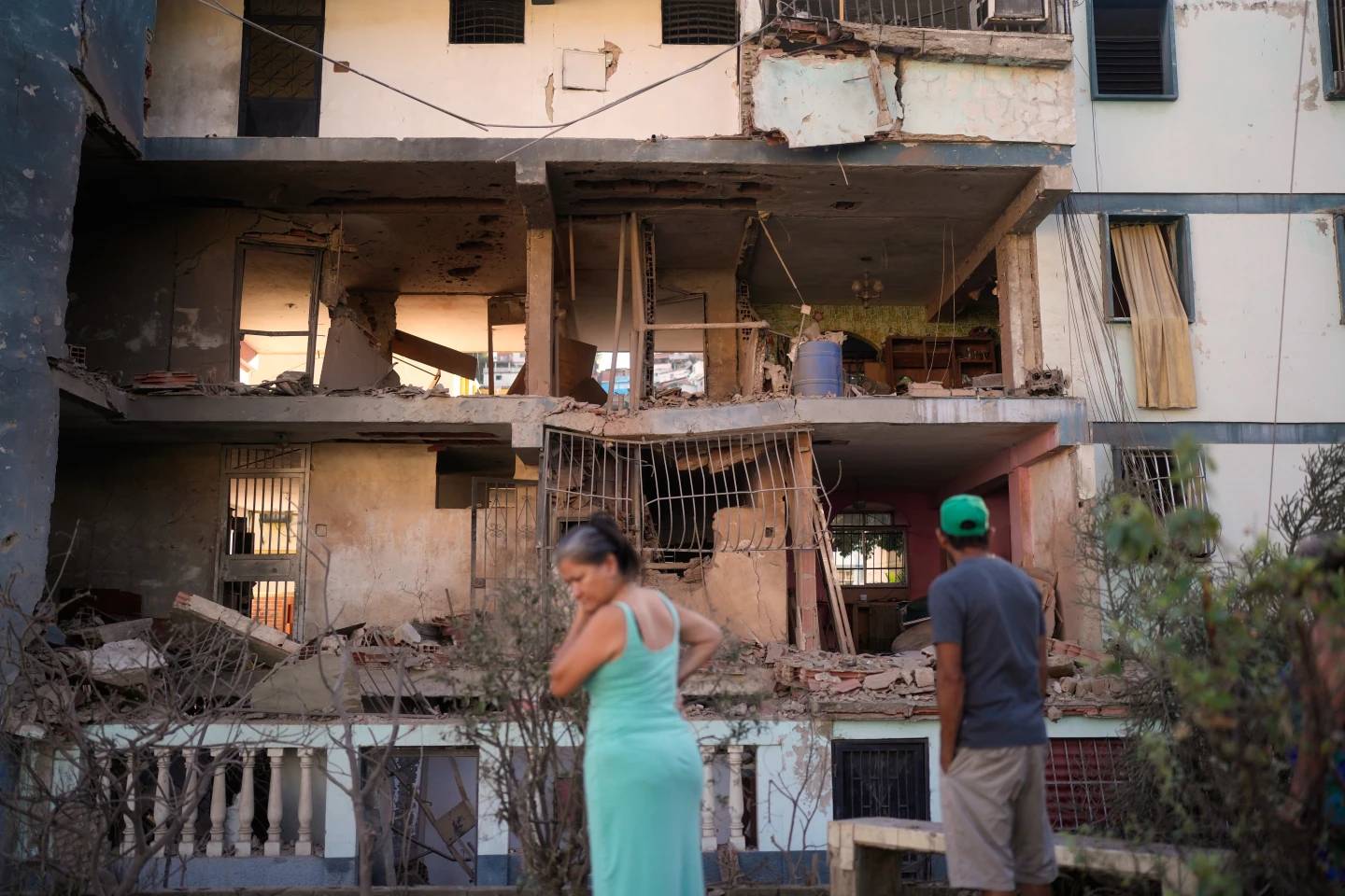 Residents look at a damaged apartment complex that neighbors say was hit during U.S. strikes to capture Venezuelan President Nicolás Maduro, in Catia La Mar, Venezuela, Sunday, Jan. 4, 2026. (Credit: Matias Delacroix/AP.)