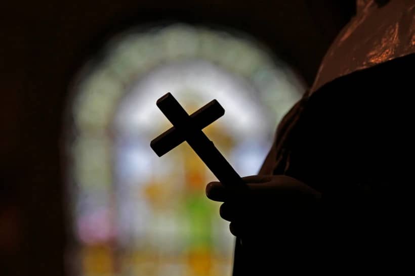 A cross is silhouetted against a stained glass window inside a Catholic Church in New Orleans on Dec. 1, 2012. (Credit: Gerald Herbert/AP.)