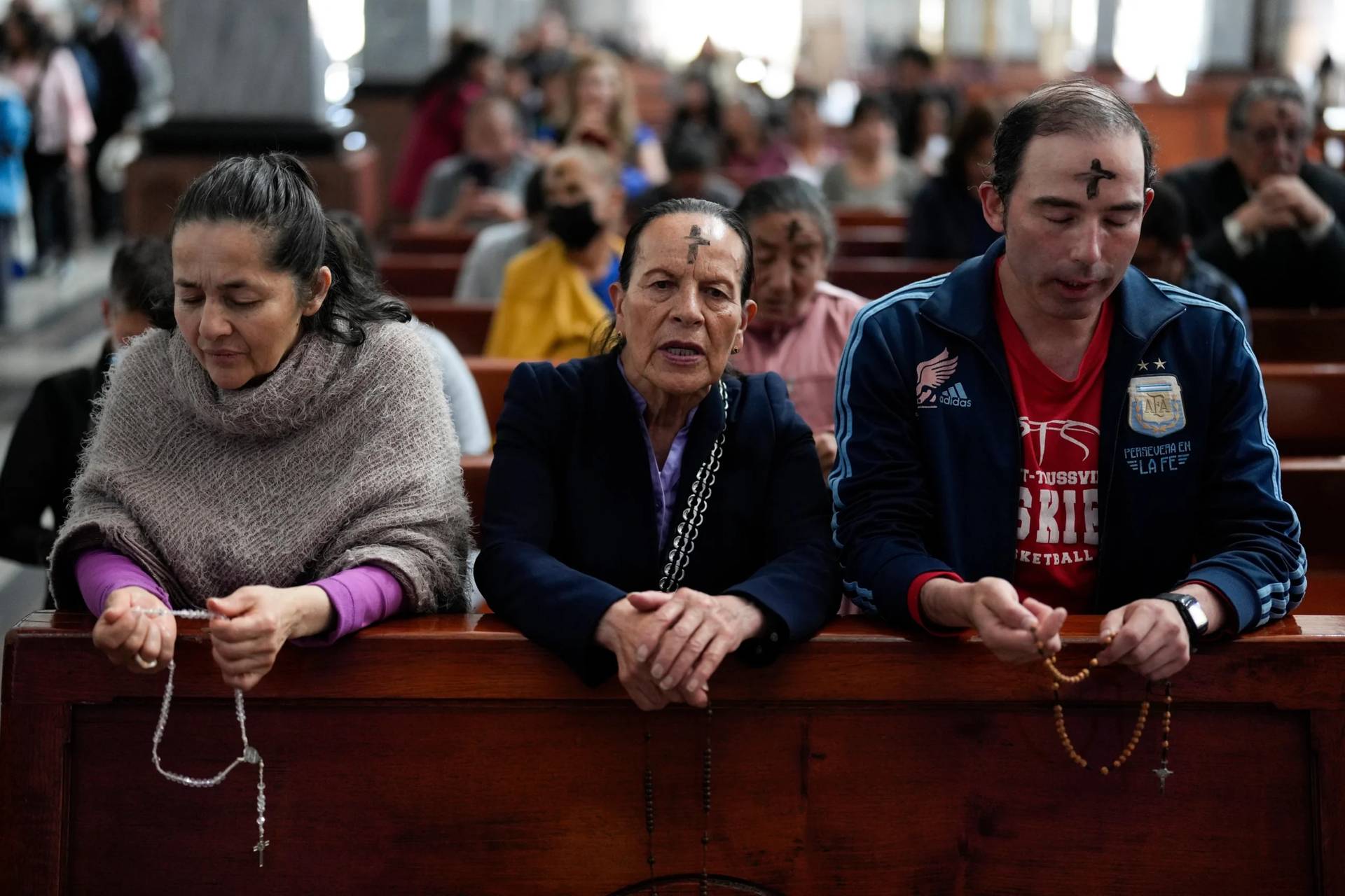 Catholics pray the rosary while a priest marks people’s foreheads with ashes during Ash Wednesday Mass at the Church of the Divine Child in Bogota, Colombia, Wednesday, Feb. 14, 2024. (Credit: Fernando Vergara/AP.)